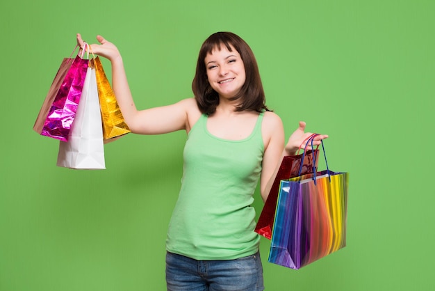 Niña feliz con coloridas bolsas de compras aisladas sobre fondo verde