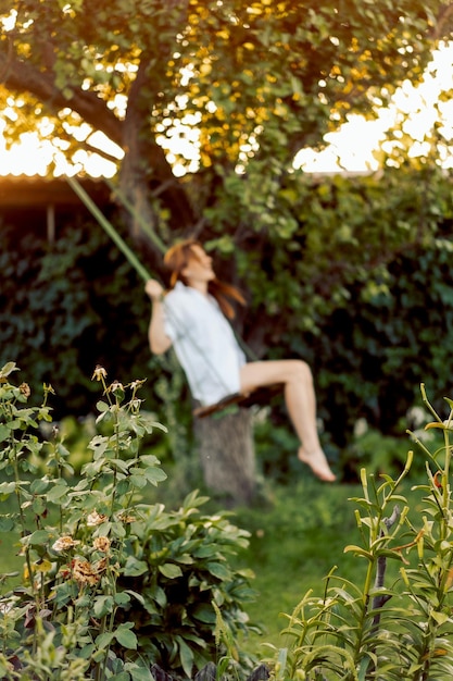 Foto niña feliz en un columpio en el jardín