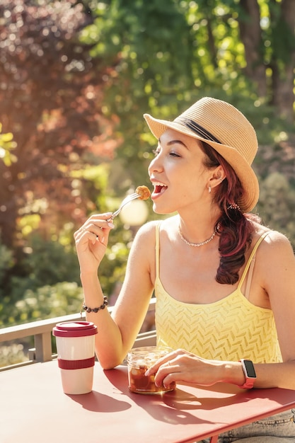 Una niña feliz come una apetitosa salchicha jugosa currywurst alemana tradicional con condimentos en un café al aire libre