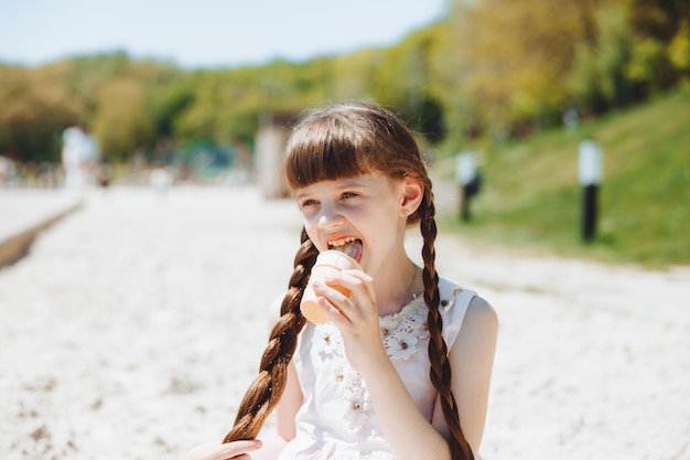 Niña feliz comiendo helado en la playa en verano vacaciones de verano