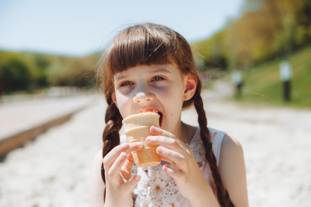 Niña feliz comiendo helado en la playa en verano vacaciones de verano