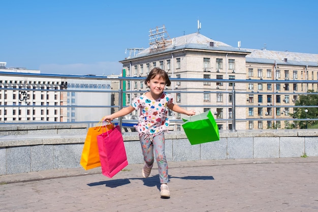 La niña feliz con compras corre en una reunión con los padres.