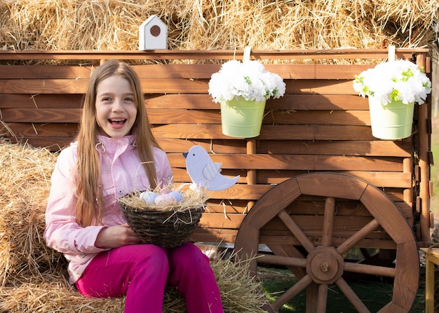 niña feliz con conejito de pascua y huevos al aire libre