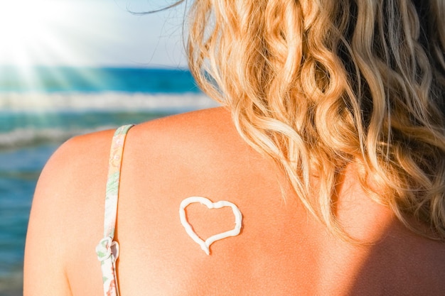 Niña feliz con un corazón en la espalda por el mar al aire libre