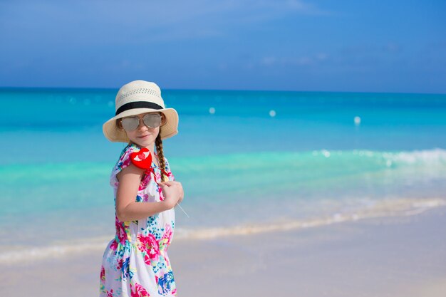 Niña feliz con corazón rojo en manos en una playa tropical