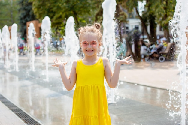 Una niña feliz corre cerca de la fuente en el verano en el parque.