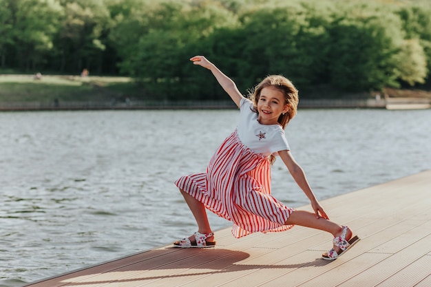 Niña feliz corre y salta en el paseo marítimo Disfrute de la libertad de la naturaleza Vida después de la cuarentena