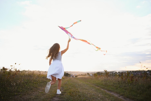 Foto una niña feliz corriendo en el campo con cometa