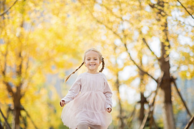 Niña feliz corriendo en el parque otoñal