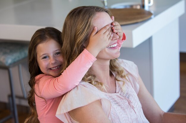 Niña feliz cubriendo sus ojos de madre