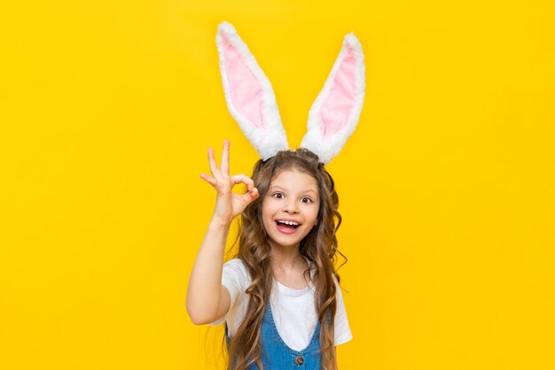 Una niña feliz disfruta de las vacaciones de primavera de Pascua para niños Un niño vestido como un conejo con orejas largas Una dama encantadora con el pelo rizado sobre un fondo amarillo aislado