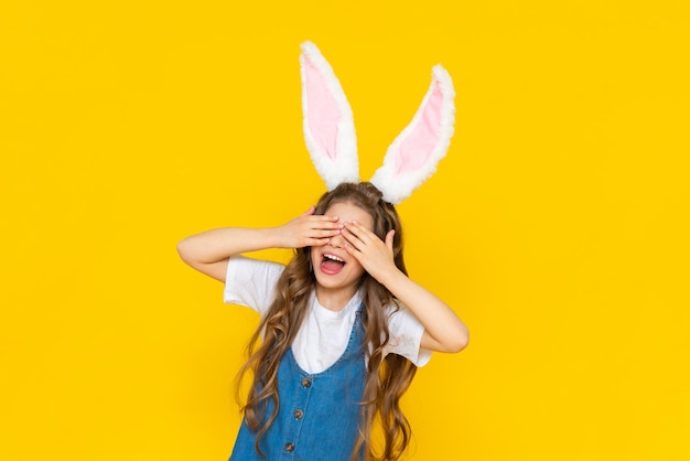 Una niña feliz disfruta de las vacaciones de primavera de Pascua para niños Un niño vestido como un conejo con orejas largas Una dama encantadora con el pelo rizado sobre un fondo amarillo aislado
