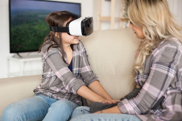 Niña feliz disfrutando de su casco de realidad virtual. Madre joven.