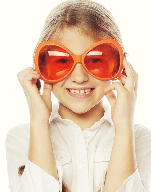 Niña feliz con divertidas gafas de carnaval naranja