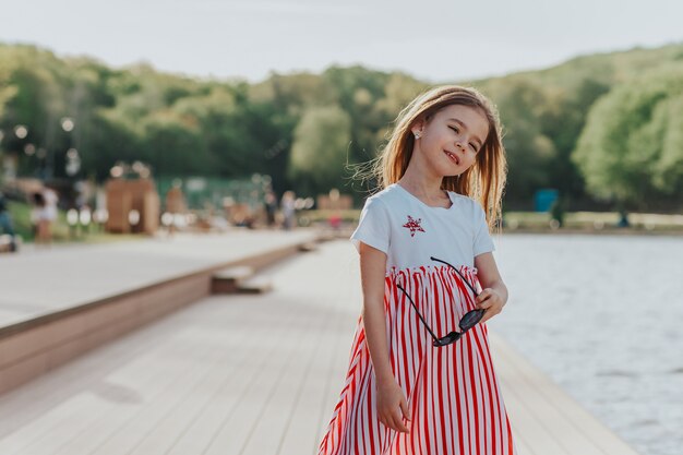 Niña feliz divirtiéndose con gafas de sol en el paseo marítimo Disfrute de la libertad de la naturaleza