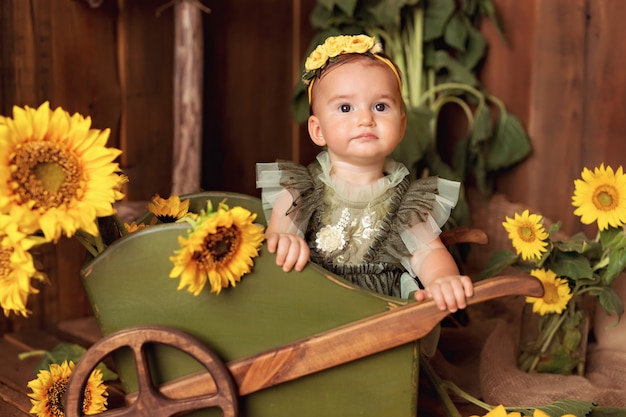 Niña feliz divirtiéndose y jugando entre girasoles florecientes cerca del carro