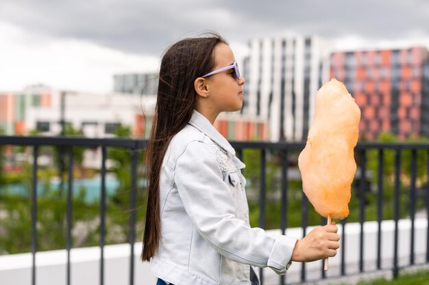 Niña feliz con dulce algodón de azúcar en el parque de verano.