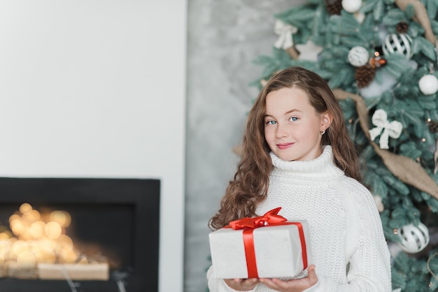 Niña feliz emocionada con caja de regalo de Navidad.