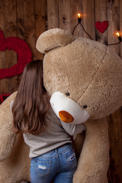 Niña feliz con un enorme oso se encuentra de espaldas