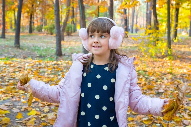 Una niña feliz está jugando en un hermoso parque de otoño en un día soleado Juegos en la naturaleza