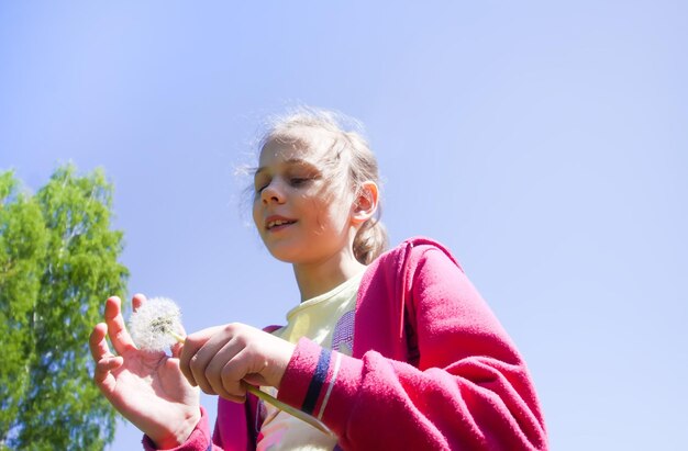 Una niña feliz con una flor de diente de león al aire libre