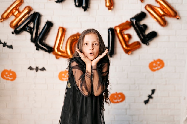 niña feliz en el fondo de la pared decorada con globos de Halloween