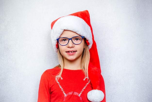 Niña feliz con gafas y gorro de Papá Noel durante las vacaciones de Navidad y Año Nuevo