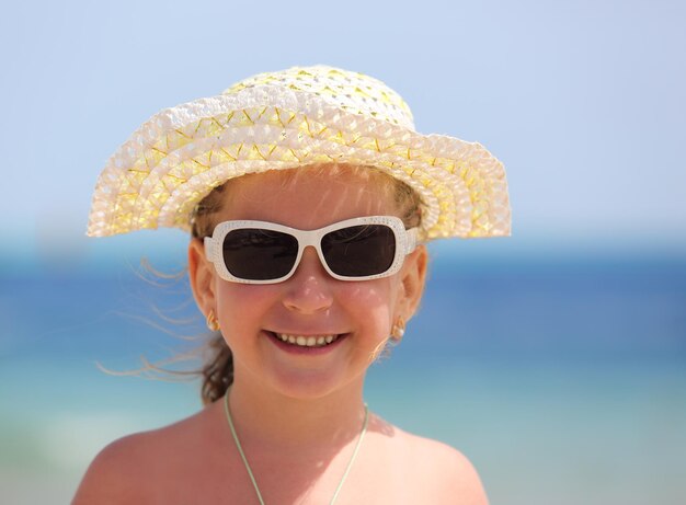 Niña feliz en gafas de sol en la playa