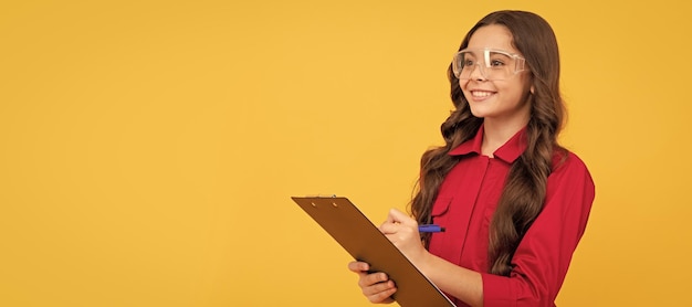 niña feliz con gafas sosteniendo una carpeta de papel educación niño constructor con gafas protectoras diseño de cartel horizontal espacio de copia de encabezado de banner