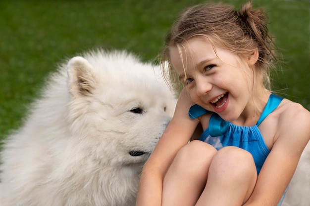 niña feliz y un gran perro blanco sobre el césped