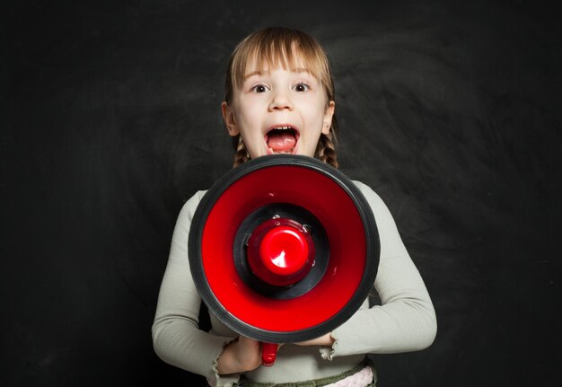 Foto niña feliz gritando a través de un megáfono en negro