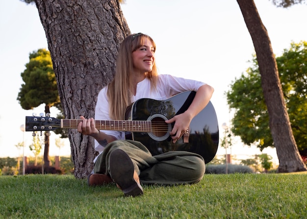 Niña feliz con guitarra divirtiéndose al aire libre