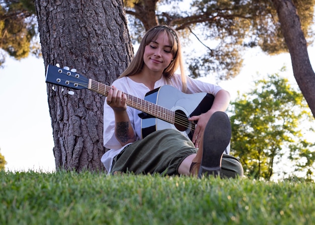 Niña feliz con guitarra divirtiéndose al aire libre