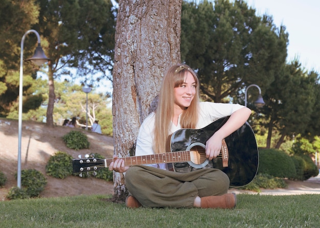 Foto niña feliz con guitarra divirtiéndose al aire libre