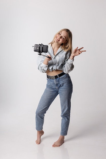 Foto niña feliz haciendo autorretrato con teléfono inteligente conectado a selfie stick