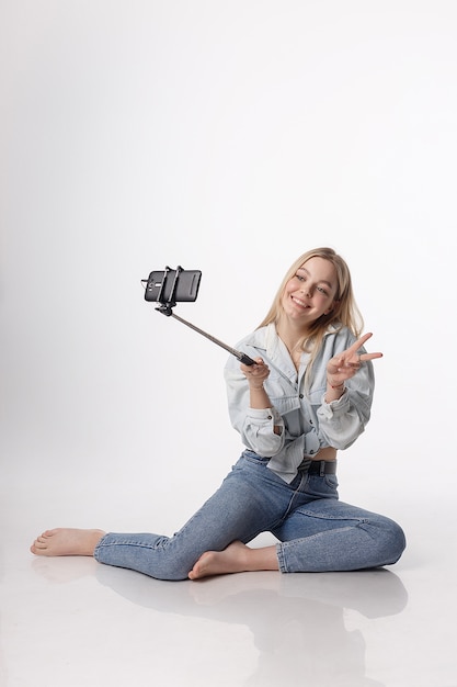 Niña feliz haciendo autorretrato con teléfono inteligente conectado a selfie stick