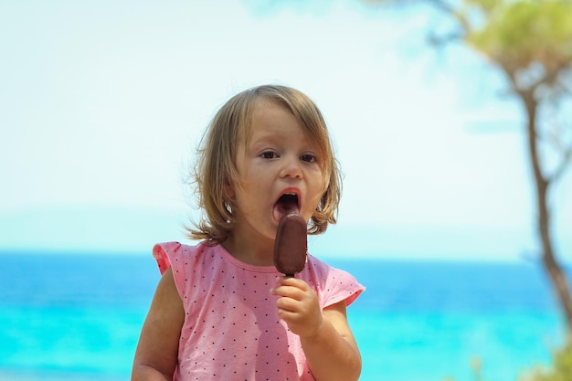Una niña feliz con helado junto al mar en la naturaleza en el viaje del parque