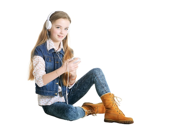 Niña feliz en jeans escuchando música con smartphone