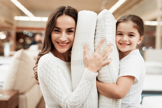 Niña feliz y joven abrazando las almohadas