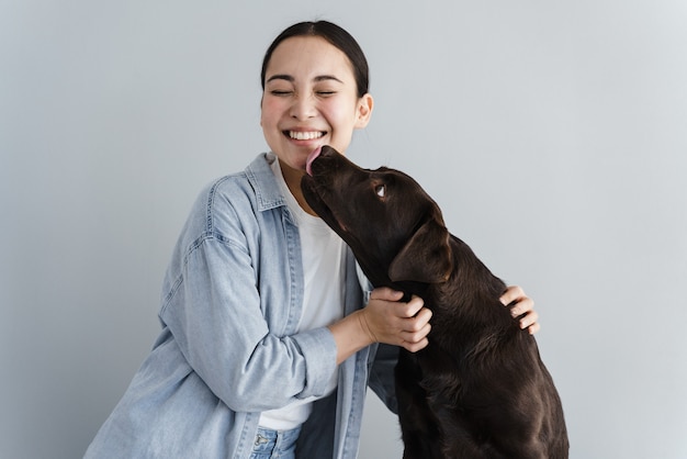 Niña feliz juega con perro sobre fondo gris