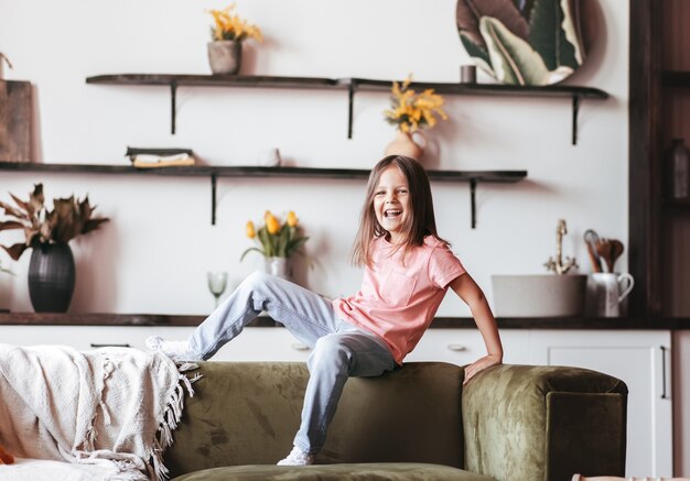 Foto niña feliz jugando alegremente en el sofá de la sala de estar