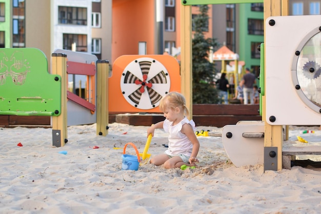 Niña feliz jugando en el arenero Parque infantil moderno Recreación activa en la ciudad