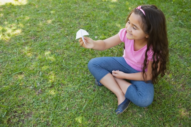 Niña feliz jugando con un avión de papel en el parque