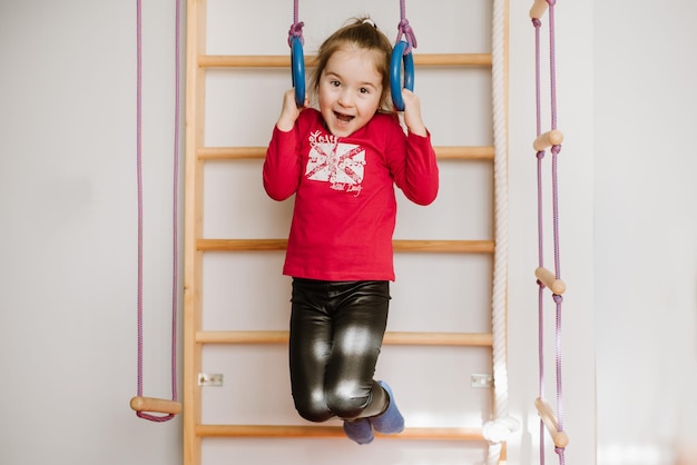 Niña feliz jugando en las barras de mono y diviértete en casa