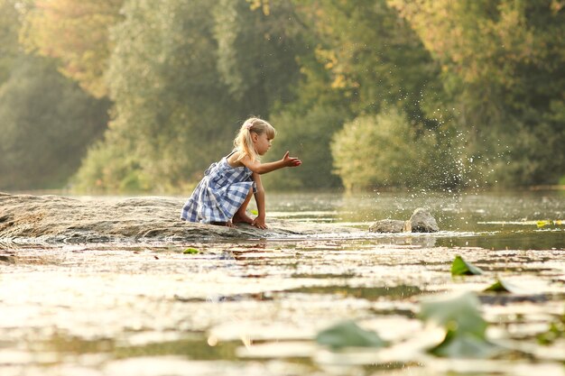 Niña feliz jugando cerca del río salpicaduras de agua