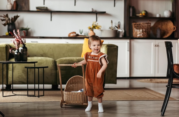 Niña feliz jugando con un cochecito en la habitación de los niños Niña jugando con un cochecito Cochecito de bebé