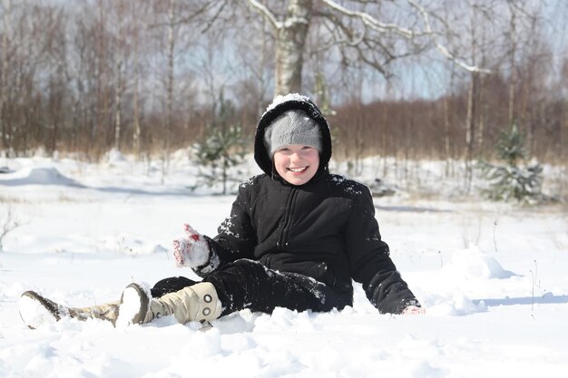 Niña feliz jugando con nieve al aire libre en invierno en el campo