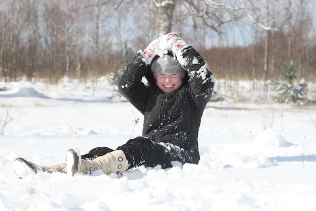 Niña feliz jugando con nieve al aire libre en invierno en el campo