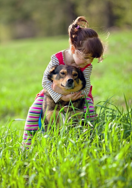 Niña feliz jugando con el perro en la hierba