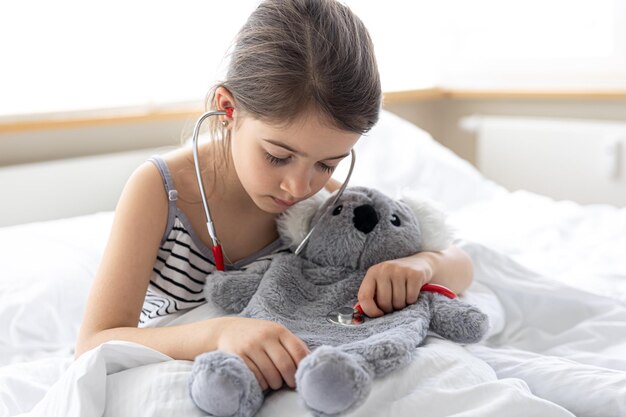 Niña feliz con koala de peluche en la cama